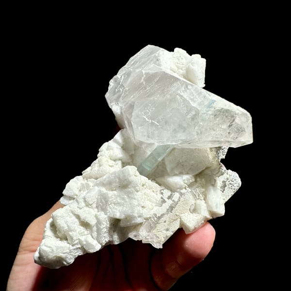 Pale aquamarine prism crossing clear quartz on feldspar from Pakistan, close-up of the crystal faces
