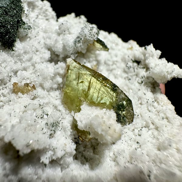 Yellow-green titanite crystal on white druse with chlorite from Pakistan, close-up of the crystal faces