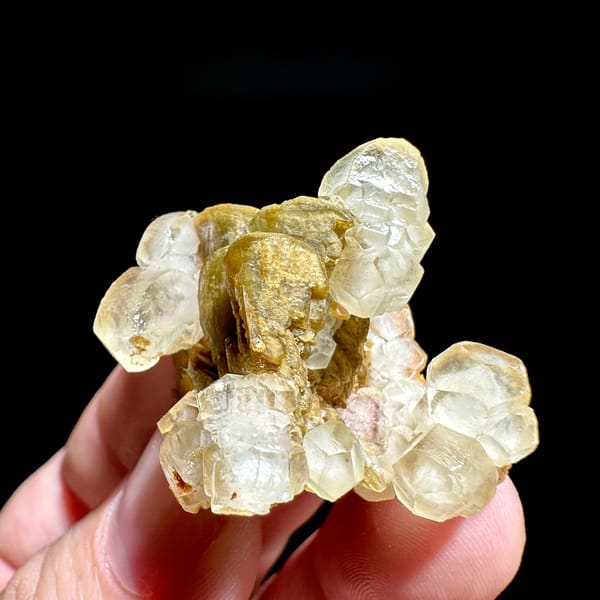 Translucent calcite rhombs around golden siderite from Guizhou, China, held in hand