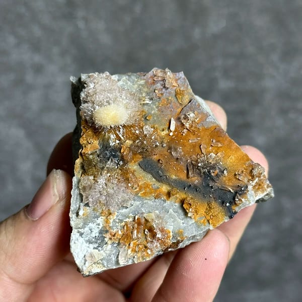 Sunflower creedite sprays on rust-and-grey matrix from Guizhou, China, held in hand
