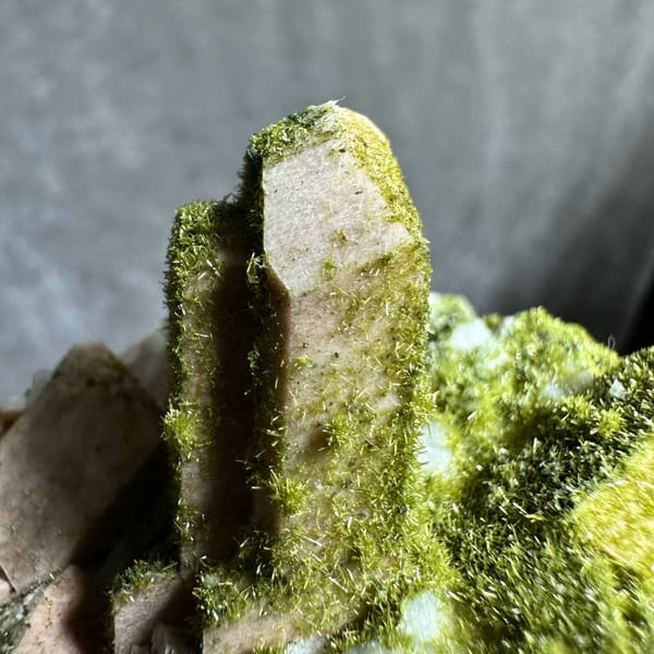 Lime-green epidote-coated feldspar prism on white base from Yunxiao, Fujian, China, close-up of the crystal faces