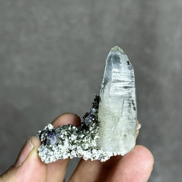 Tall clear quartz prism with purple fluorite and mica from Yaogangxian Mine, Hunan, China, detail of the matrix contact
