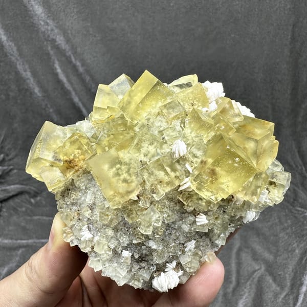 Mound of glassy lemon-yellow fluorite cubes with baryte from Beijing, China, detail of the matrix contact