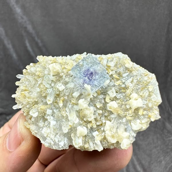 Pale blue fluorite cube on cream dolomite and quartz from Inner Mongolia, China, held in hand