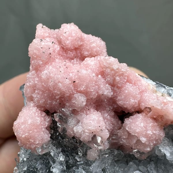 Rose-pink rhodochrosite over grey quartz with pyrite from Guangxi, China, close-up of the crystal faces