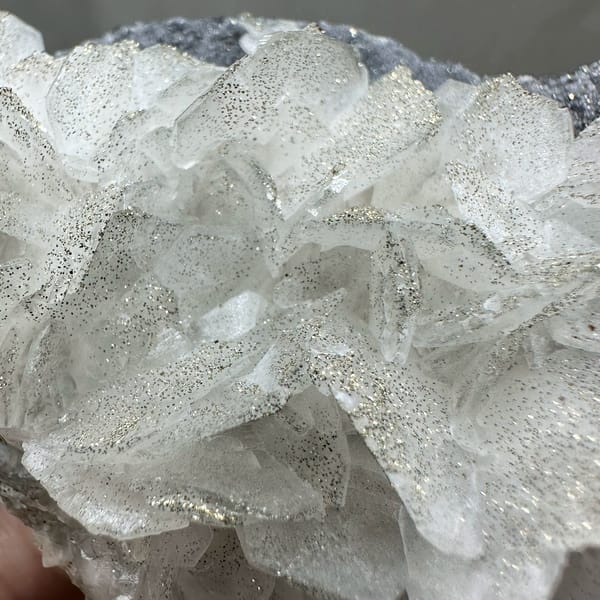 Frosted white calcite crystals on dark pyrite-dusted plate from Fujian, China, close-up of the crystal faces