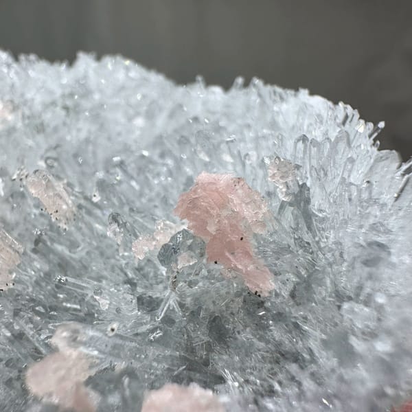 Pink rhodochrosite flecks in frosted white quartz cluster from Guangxi, China, close-up of the crystal faces