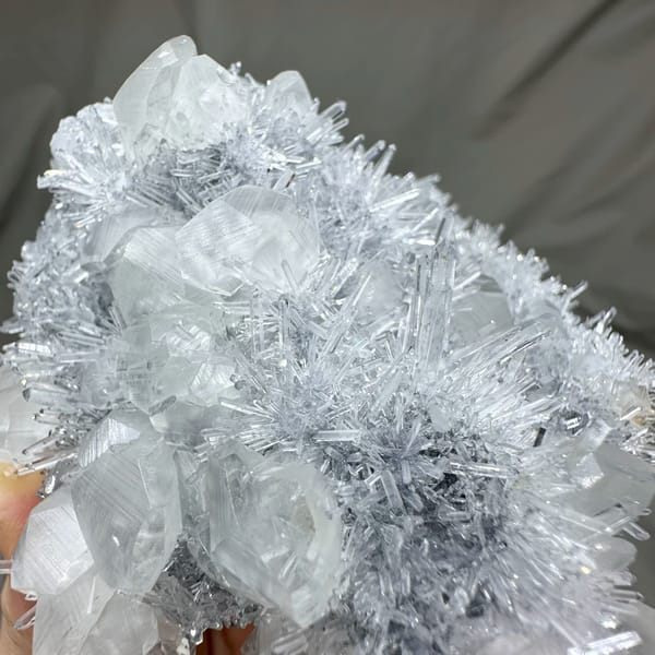 Frosted quartz needles around pale calcite prisms from Fujian, China, close-up of the crystal faces