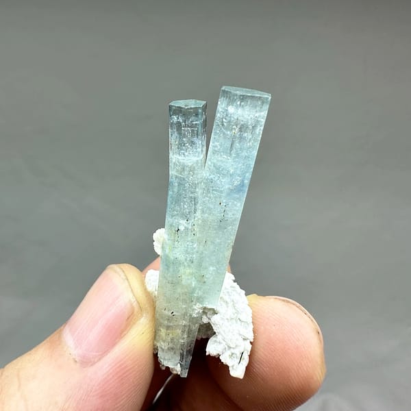 Two sea-blue aquamarine prisms on white feldspar from Namibia, close-up of the crystal faces