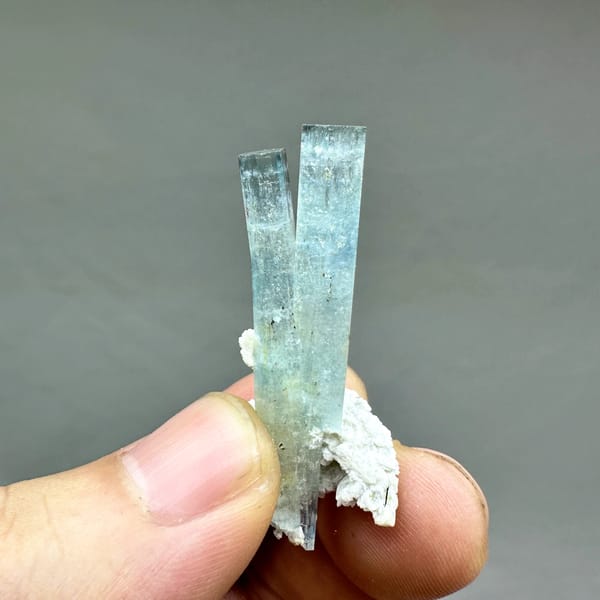 Two sea-blue aquamarine prisms on white feldspar from Namibia, reverse side