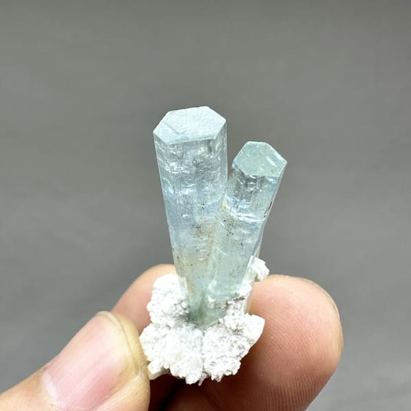 Two sea-blue aquamarine prisms on white feldspar from Namibia, detail of the matrix contact