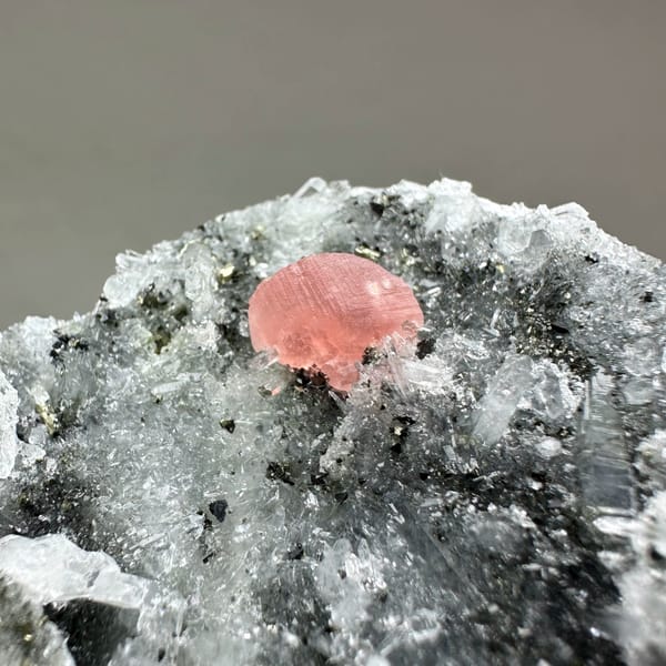 Pink rhodochrosite patch on dark quartz-and-pyrite plate from Guangxi, China, close-up of the crystal faces