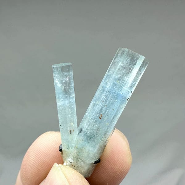 Two sky-blue aquamarine prisms with black tourmaline from Namibia, close-up of the crystal faces