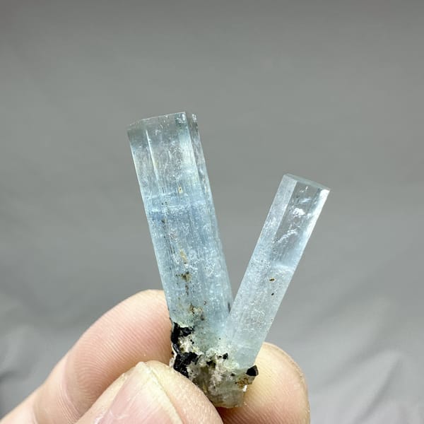 Two sky-blue aquamarine prisms with black tourmaline from Namibia, detail of the matrix contact