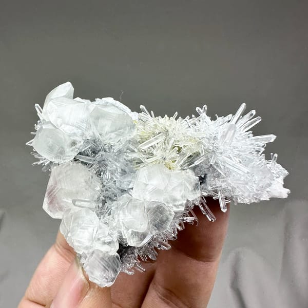 Clear quartz needles with white calcite prisms and pyrite from Fujian, China, held in hand