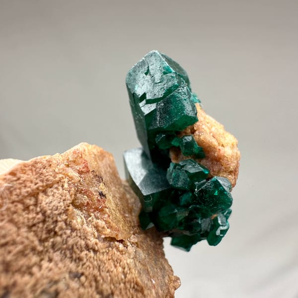 Large emerald-green dioptase crystals on pink matrix from DR Congo, close-up of the crystal faces