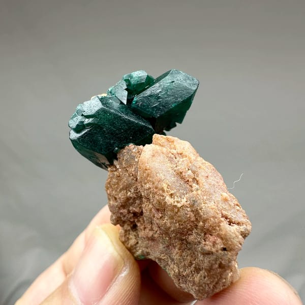 Large emerald-green dioptase crystals on pink matrix from DR Congo, reverse side