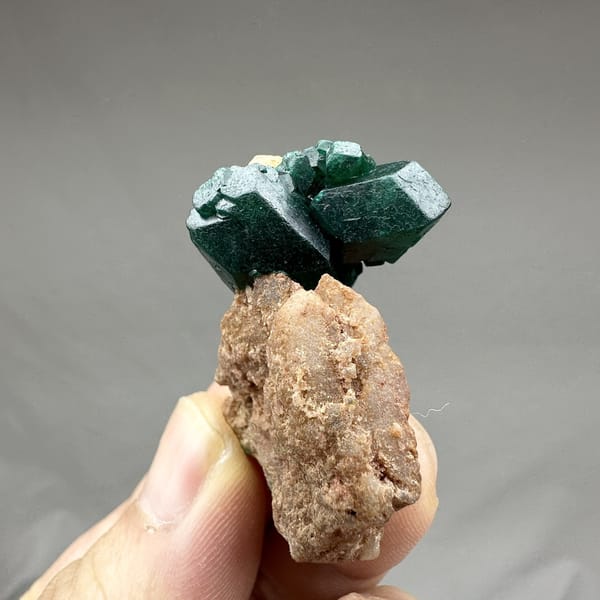 Large emerald-green dioptase crystals on pink matrix from DR Congo, detail of the matrix contact