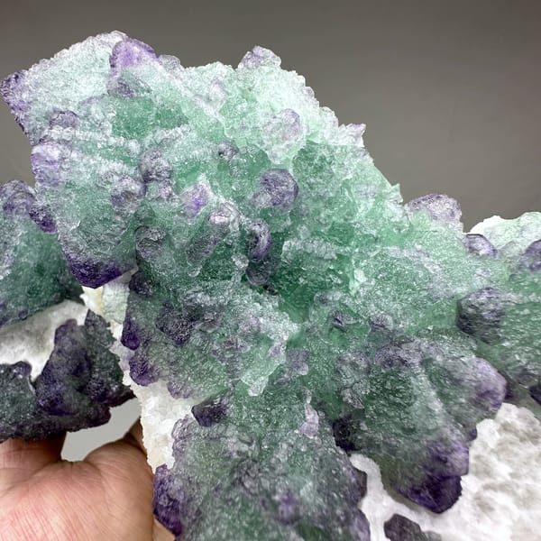 Purple and green stepped octahedral fluorite over white quartz from Zhejiang, China, close-up of the crystal faces