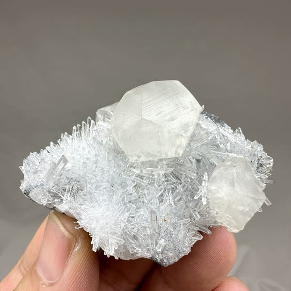 Large translucent calcite crystal in nest of quartz needles from Fujian, China, held in hand