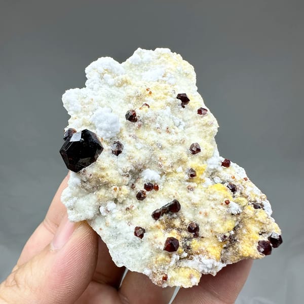 Large dark garnets with hyalite opal on cream feldspar from Yunxiao, Fujian, China, top view