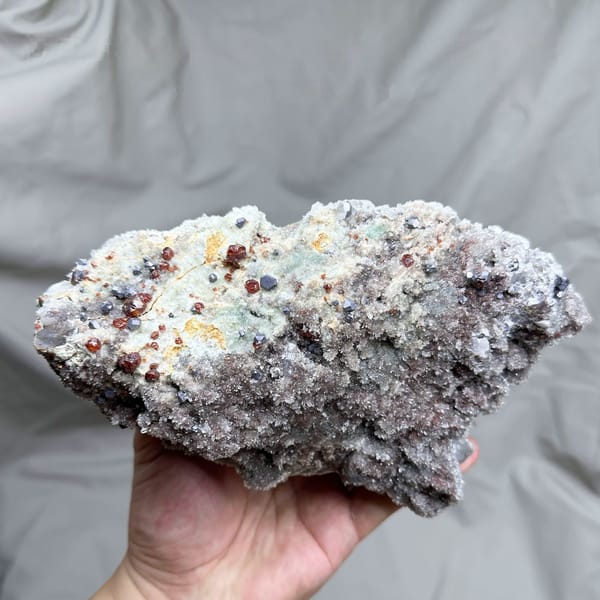 Large plate of red hematoid quartz with sphalerite and galena from Hunan, China, held in hand