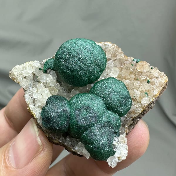 Three large velvet-green malachite balls on white quartz from DR Congo, close-up of the crystal faces