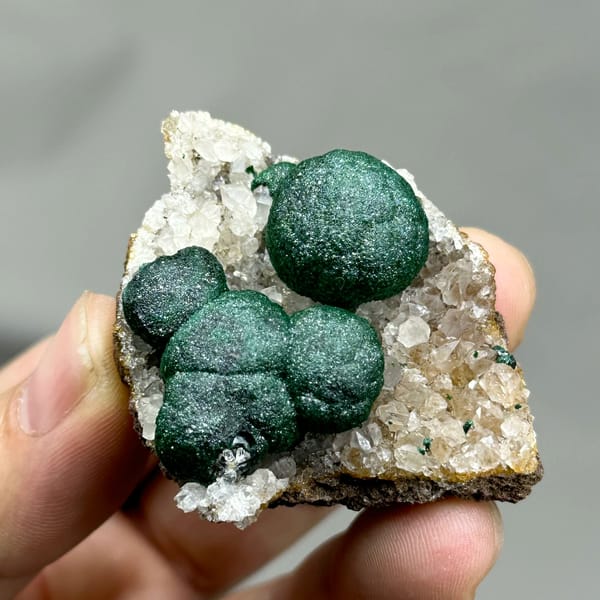 Three large velvet-green malachite balls on white quartz from DR Congo, top view