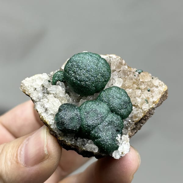 Three large velvet-green malachite balls on white quartz from DR Congo, detail of the matrix contact