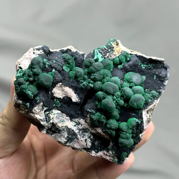 Green malachite balls over black manganese oxide from DR Congo, close-up of the crystal faces