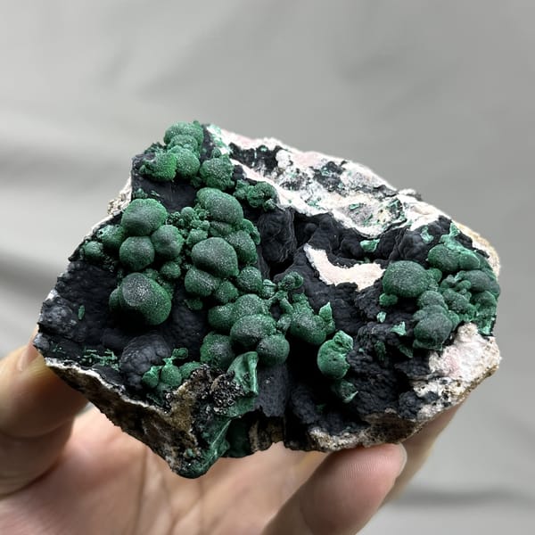 Green malachite balls over black manganese oxide from DR Congo, detail of the matrix contact