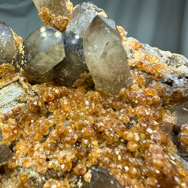 Smoky quartz points over Fanta-orange garnet druse from Yunxiao, Fujian, China, reverse side