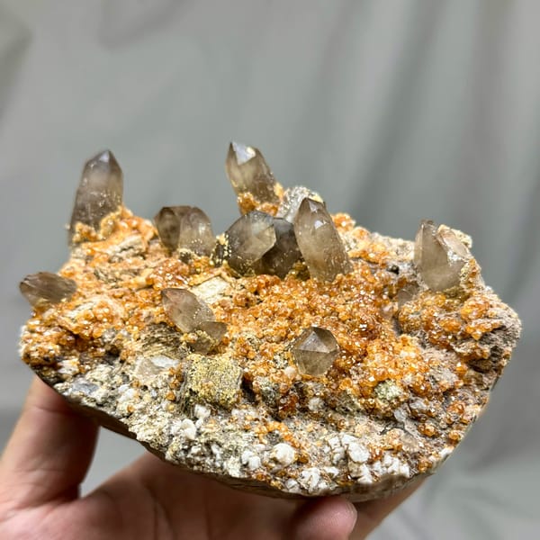 Smoky quartz points over Fanta-orange garnet druse from Yunxiao, Fujian, China, top view