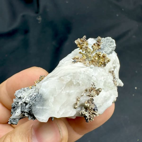 Iridescent dendritic native silver on white calcite from the USA, held in hand