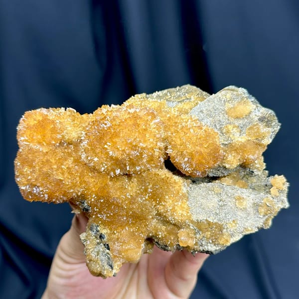 Golden-amber calcite with sparkling crystal skin from Inner Mongolia, China, held in hand