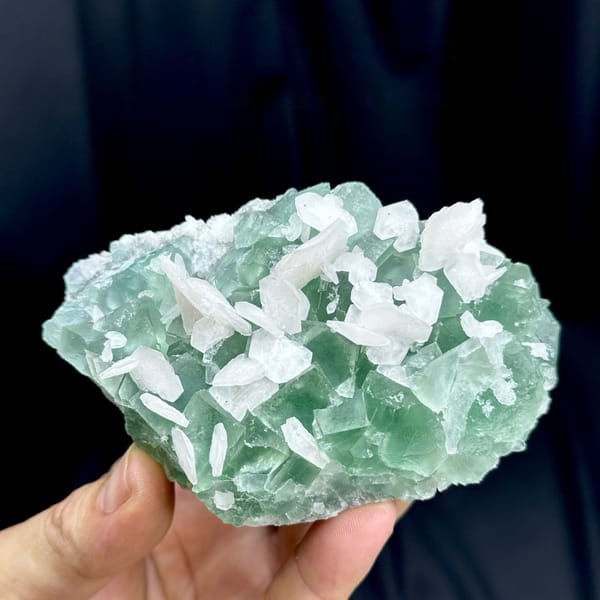 White calcite blades over mint-green fluorite from Fujian, China, held in hand