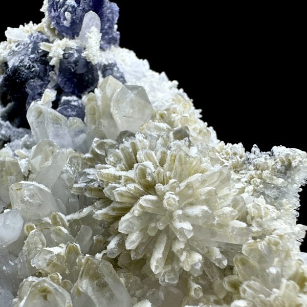 Violet fluorite cubes beside chrysanthemum quartz spray on white druse from Fujian, China, close-up of the crystal faces