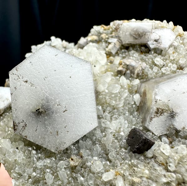 Hexagonal sandwich calcite plates with limonite on grey druse from Fujian, China, close-up of the crystal faces