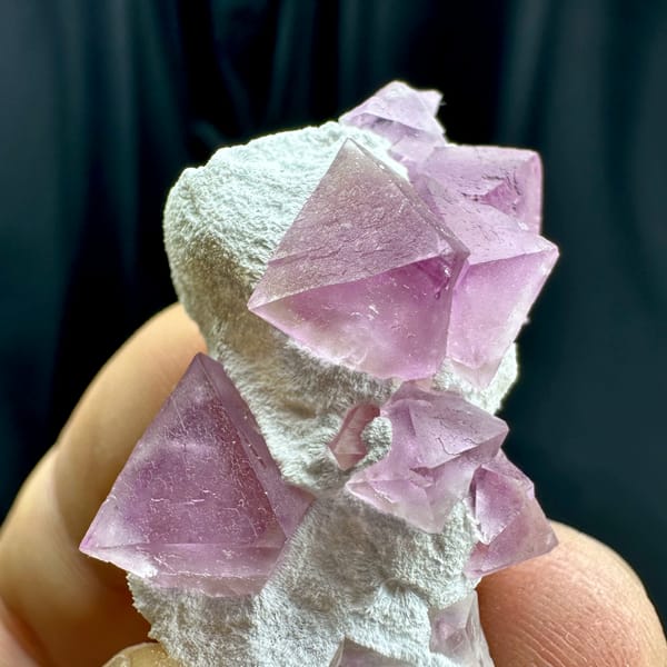 Pink fluorite octahedra on white druse stalk from Zhejiang, China, close-up of the crystal faces