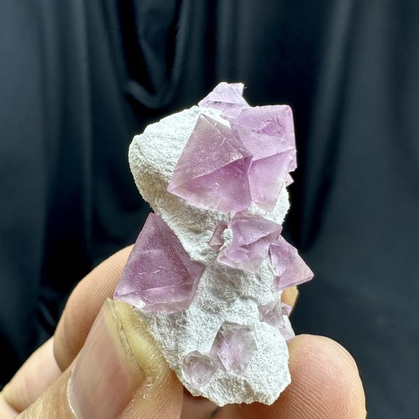 Pink fluorite octahedra on white druse stalk from Zhejiang, China, detail of the matrix contact