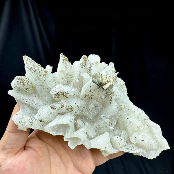 Pale quartz pseudomorphs after calcite with pyrite from Fujian, China, held in hand