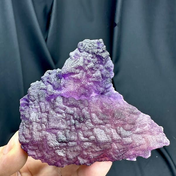 Magenta-purple stepped fluorite plate from Guizhou, China, held in hand