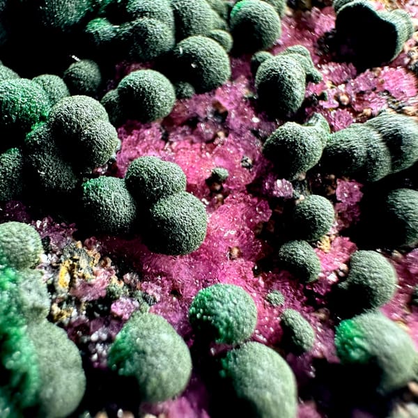 Green malachite balls over hot-pink cobaltoan calcite from DR Congo, close-up of the crystal faces