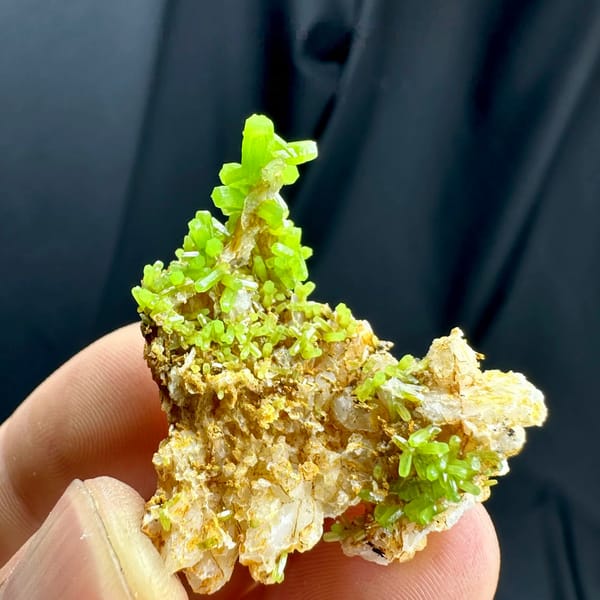 Bright lime-green pyromorphite tufts on tan matrix from Guangxi, China, held in hand