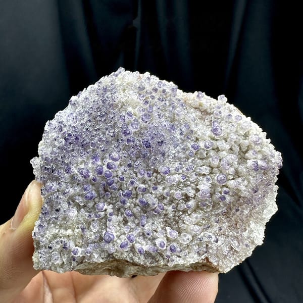 Purple yttrofluorite balls on white gypsum mound from Guizhou, China, detail of the matrix contact