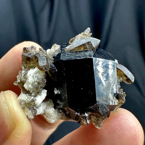 Jet-black tourmaline crystal with smoky quartz and feldspar from Namibia, close-up of the crystal faces