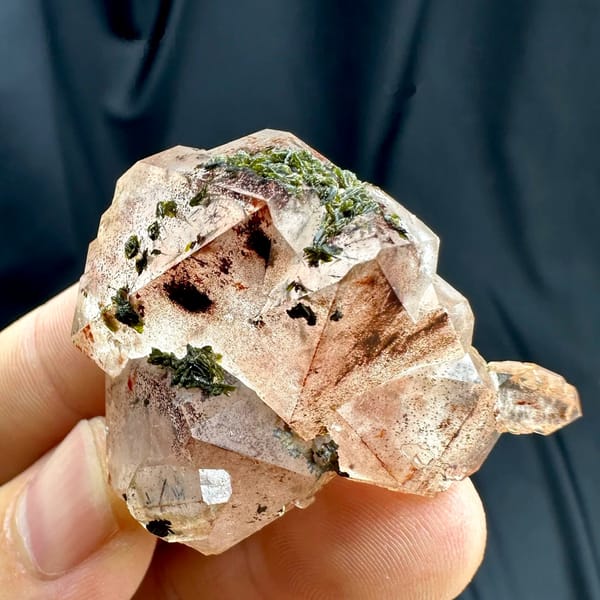 Orange-red garden quartz floater with green epidote from Sichuan, China, held in hand