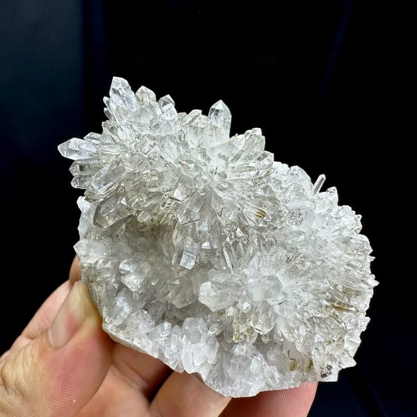 Chrysanthemum-quartz cluster of radiating clear needles from Fujian, China, held in hand