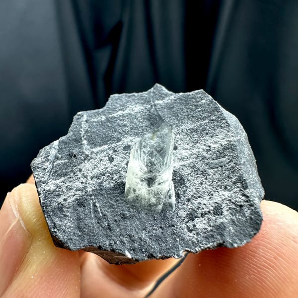 Sword-tip transparent baryte blade on dark grey rock from Guangxi, China, close-up of the crystal faces