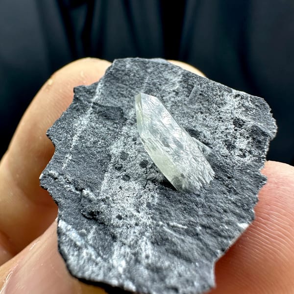 Sword-tip transparent baryte blade on dark grey rock from Guangxi, China, reverse side